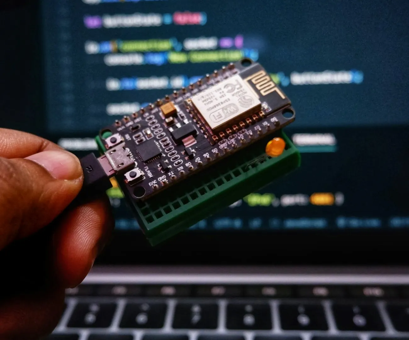 Kỹ sư cầm thiết bị IoT trước màn hình lập trình